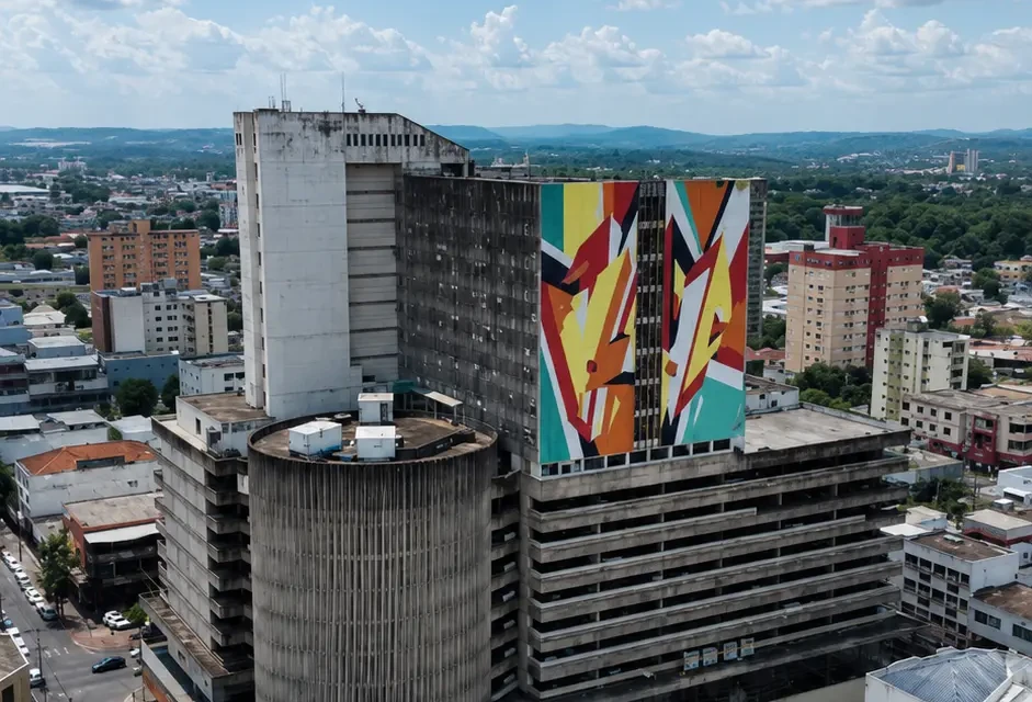 Vista aérea do Parthenon Center, edifício modernista inaugurado em 1976 no Centro de Goiânia, com torre comercial, garagem vertical e mural colorido.