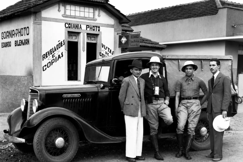 Registro em frente ao Goiânia Photo, estúdio de Eduardo Bilemjian em Campinas, mostra o fotógrafo e outros homens ao lado de um veículo usado no período em que ele documentava os primeiros anos da nova capital. (Foto: Acervo Eduardo Bilemjian)