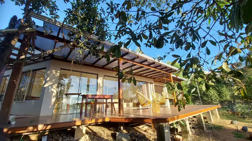 Casa Jagô, em Alto Paraíso de Goiás, combina grandes portas de vidro, deck panorâmico e vista para as montanhas da Chapada dos Veadeiros, aproximando a arquitetura da paisagem do Cerrado. (Foto: Reprodução/Airbnb)