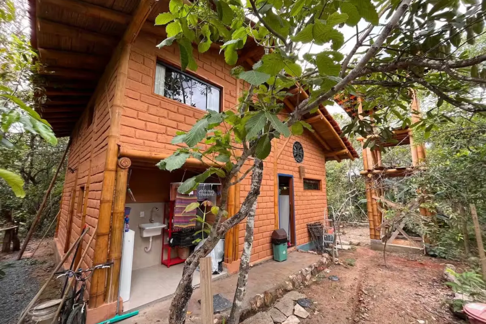 Cabana Belchior, em Cavalcante, foi construída com bambu e adobe e aposta em arquitetura bioclimática integrada à vegetação da Chapada dos Veadeiros. A hospedagem fica cercada pela mata e a poucos minutos do centro da cidade. (Foto: Reprodução/Airbnb)