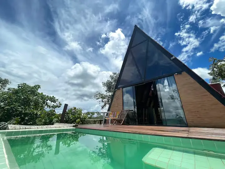 Cabana Energia, em Pirenópolis, fica cercada pelo Cerrado e tem piscina com vista para as serras e o vale, em uma proposta que combina isolamento, natureza e arquitetura voltada para a paisagem. (Foto: Reprodução/Airbnb)
