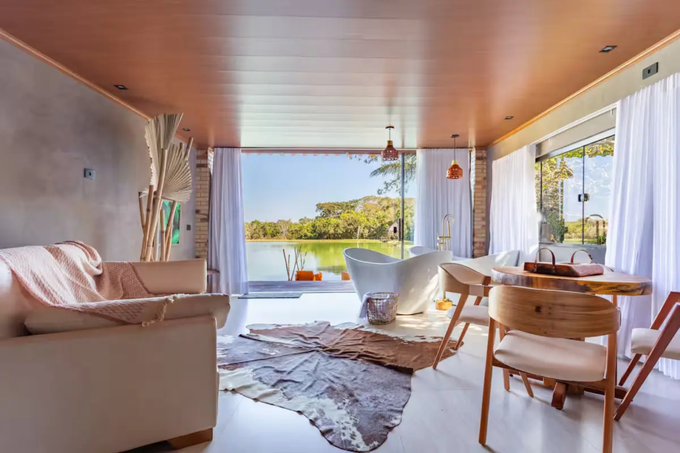 Cabana da Floresta, em Bela Vista de Goiás, tem deck voltado para o lago, quarto com vista para o bosque e duas banheiras de imersão, em uma hospedagem cercada pela natureza. (Foto: Reprodução/Airbnb)