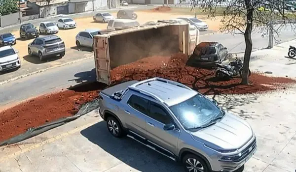 Caminhão tombado com carga de terra espalhada ao lado de carro estacionado no Jardim dos Buritis, em Aparecida de Goiânia