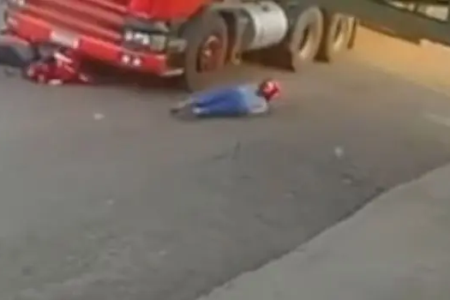Motociclista caída no asfalto ao lado de um caminhão após colisão em Rio Verde