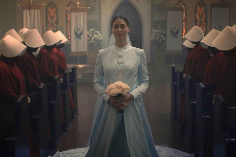 Cena de O Conto da Aia mostra uma cerimônia em Gilead, cercada pelas Aias com os tradicionais trajes vermelhos (Foto: Disney/Hulu)