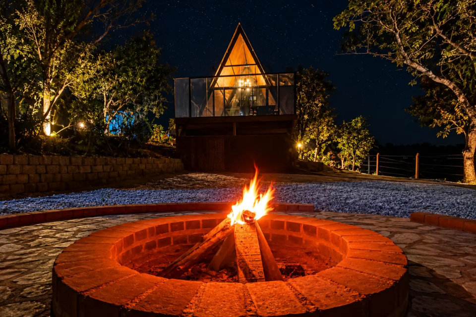 Chalé Ypê Roxo, em Pirenópolis, oferece área externa com fogueira, ambiente cercado pela natureza e estrutura voltada para hospedagem de casais (Foto: Reprodução/Airbnb)