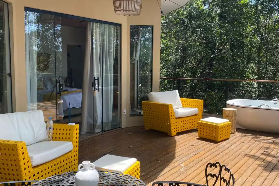 Dream Village, em Pirenópolis, é uma cabana cercada pela vegetação, com banheira de hidromassagem e três decks externos voltados para descanso, refeições e atividades físicas (Foto: Reprodução/Airbnb)