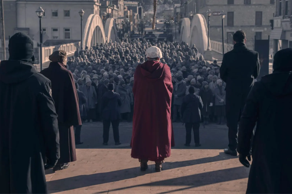 Cena de O Conto da Aia mostra uma Aia diante de uma multidão em Gilead, sob vigilância das autoridades do regime (Foto: Disney/Hulu)penultimo-episodio-da-6a-temporada-de-the-handmaids-tale