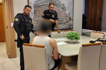 Suspeito sentado na mesa sendo ouvido por policiais - (Foto: divulgação/PC)