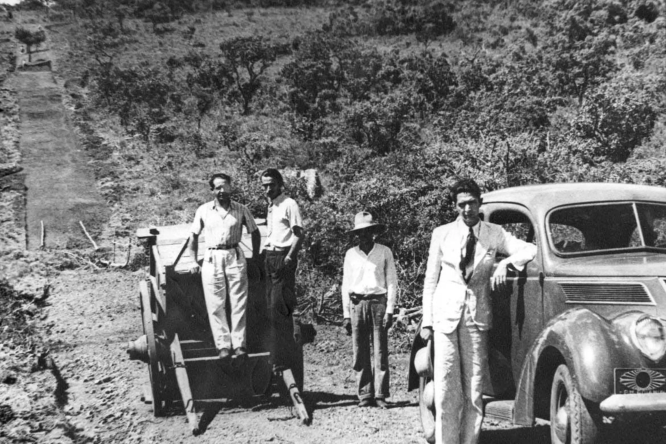 Registro histórico de abertura de estrada, com homens ao lado de maquinário e automóvel em trecho ainda sem pavimentação (Reprodução/Acervo histórico de Goiania)